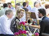 Menschen feiern bei Stehempfang in Biergarten