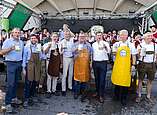 Gruppenbild: Männer mit Bierkrügen in der Hand nach Fassanstich