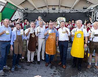 Gruppenbild: Männer mit Bierkrügen in der Hand nach Fassanstich