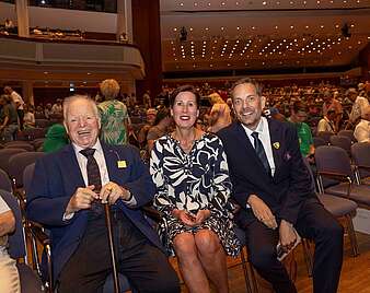 Drei Personen auf Sitzen im Theater