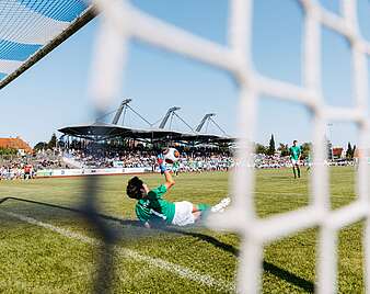 Torwart hält Fußball Zuschauer im Hintergrund auf Tribüne