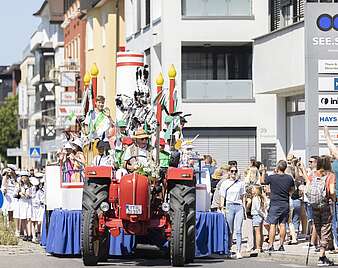 Festzug: Wagen gezogen von Traktor mit Mann in Hasenkostüm darauf