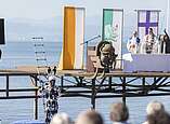 Menschen verfolgen ökumenischen Freiluftgottesdienst mit Altar auf Klangschiff, Mann in Hasenkostüm winkt