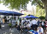 Menschen feiern bei Stehempfang in Biergarten