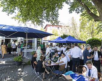 Menschen feiern bei Stehempfang in Biergarten