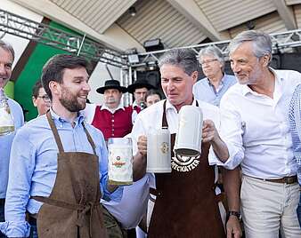 Gruppenbild: Männer mit Bierkrügen in der Hand nach Fassanstich