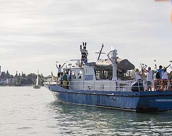 Polizeiboot fährt mit Menschen auf See