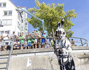 Mann in Hasenkostüm vor Ufermauer mit Menschen