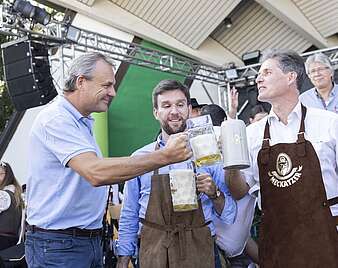 Drei Männer stoßen mit Bierkrügen an