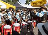 Fanfarenzug spielt und trommelt zwischen Sonnenschirmen
