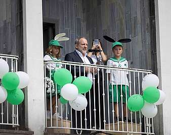 Menschen auf Balkon mit grün-weißen Luftballons