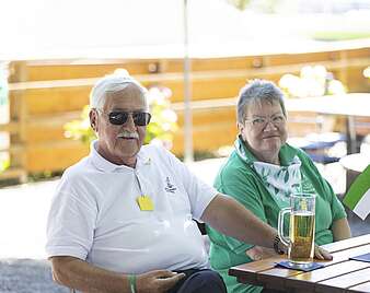 Mann und Frau sitzen an Tisch in Biergarten