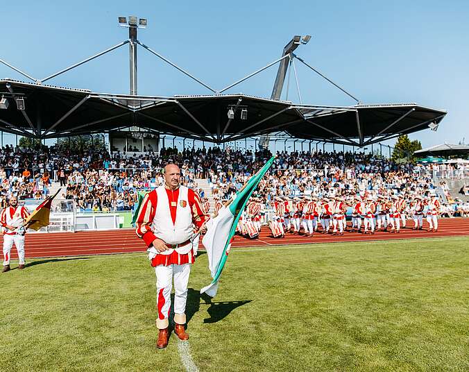 Fanfarenzug mit Fahnenschwinger auf Fußballplatz