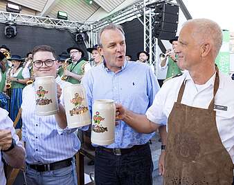 Mehrere Männer beim Fassanstich prosten sich zu