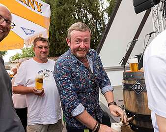 Drei Männer beim Bier zapfen aus einem Fass