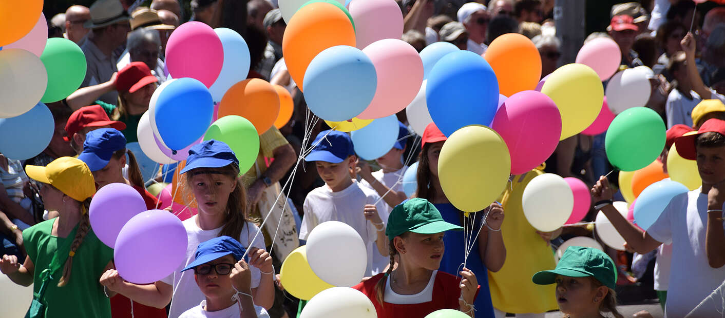 viele Kinder mit bunten Luftballons